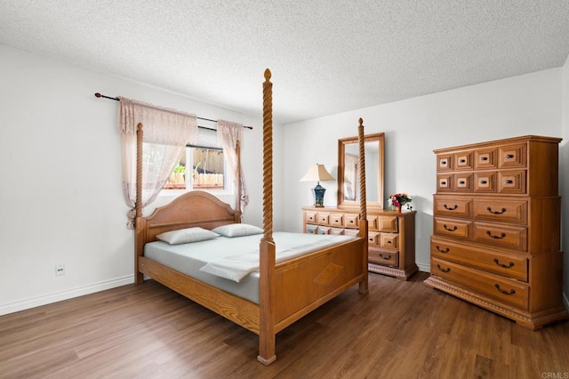 bedroom with a textured ceiling, baseboards, and wood finished floors