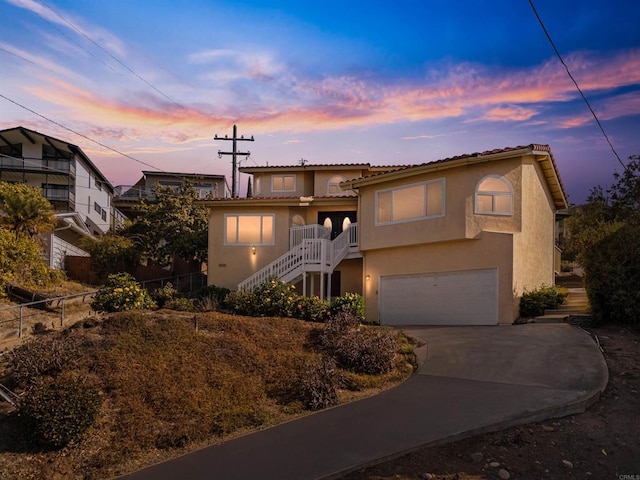 mediterranean / spanish-style home featuring stucco siding, stairway, concrete driveway, an attached garage, and a tiled roof