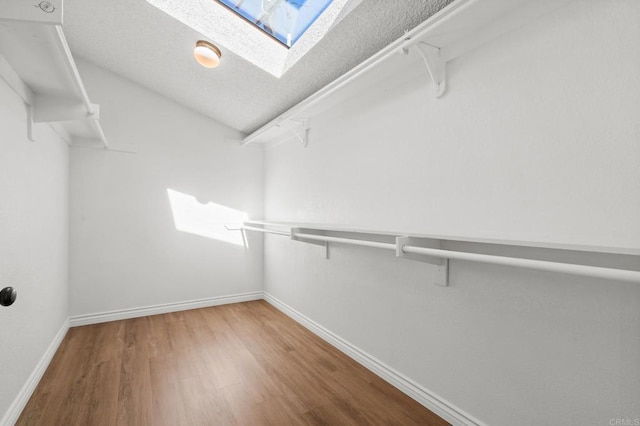 walk in closet with wood finished floors and a skylight