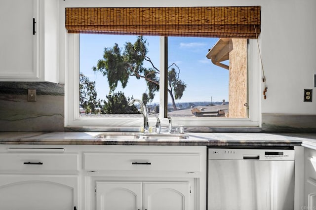 kitchen with a sink, white cabinets, stainless steel dishwasher, dark countertops, and backsplash