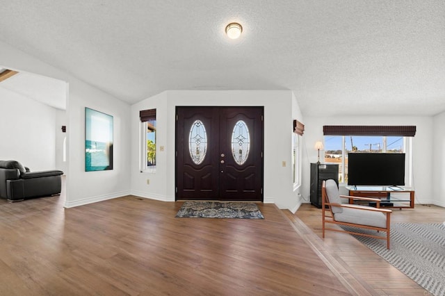 entrance foyer with wood finished floors, a wealth of natural light, and a textured ceiling