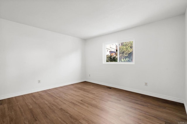 unfurnished room featuring visible vents, baseboards, and wood finished floors