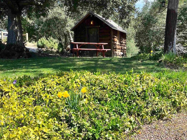 exterior space featuring an outbuilding, a lawn, and log siding