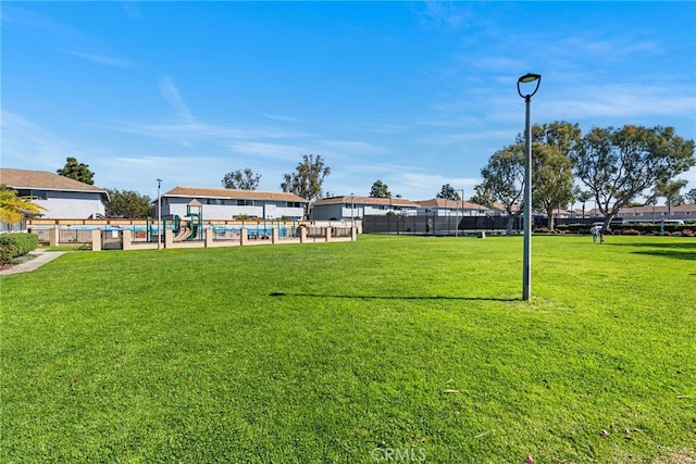 view of community with a pool, a yard, and fence