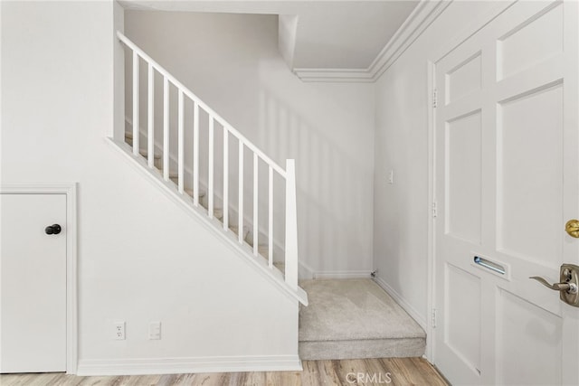 stairway with ornamental molding, baseboards, and wood finished floors