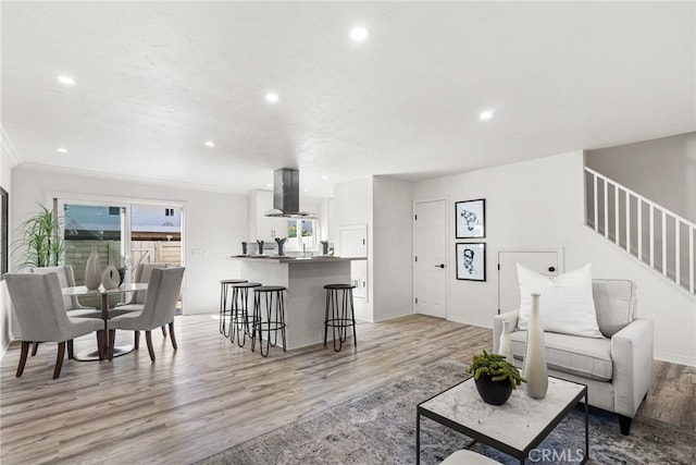 living room featuring recessed lighting, light wood-style flooring, and stairs