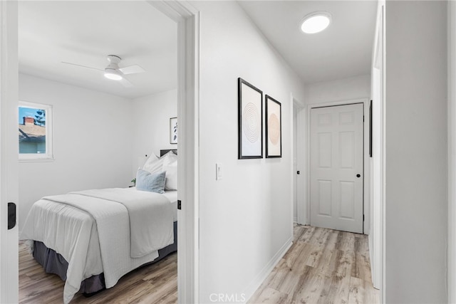 bedroom with light wood-type flooring, baseboards, and ceiling fan