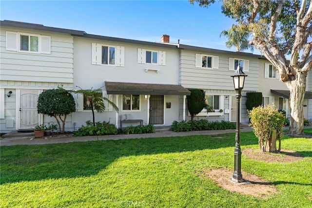 townhome / multi-family property with a chimney and a front lawn