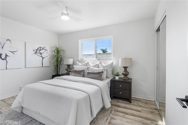 bedroom with light wood-type flooring, baseboards, a closet, and a ceiling fan