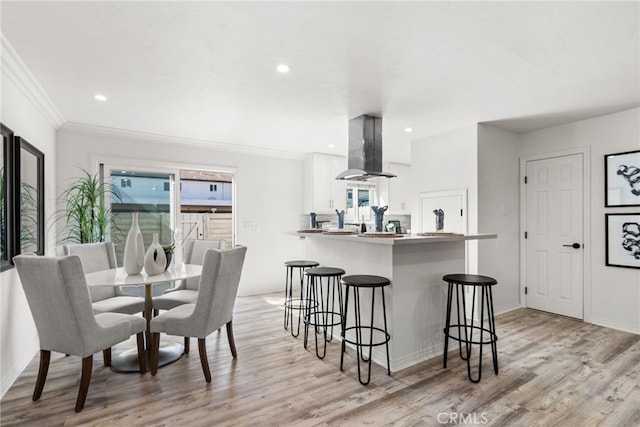 dining room featuring recessed lighting, light wood finished floors, and ornamental molding