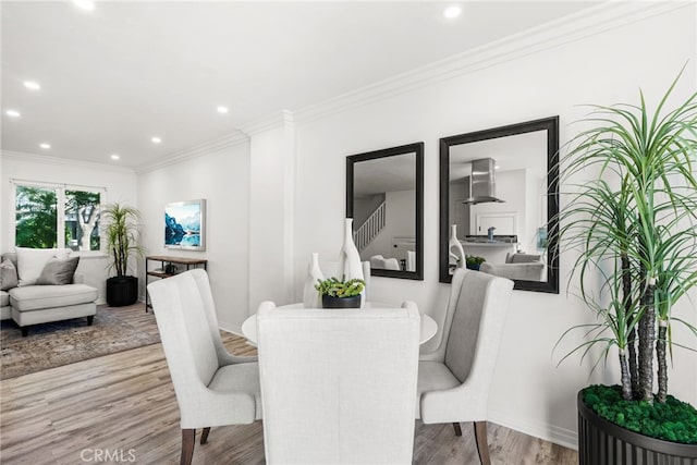 dining area with wood finished floors, baseboards, recessed lighting, ornamental molding, and stairs