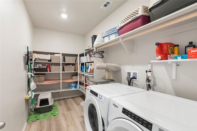 clothes washing area featuring laundry area, washing machine and dryer, visible vents, and wood finished floors