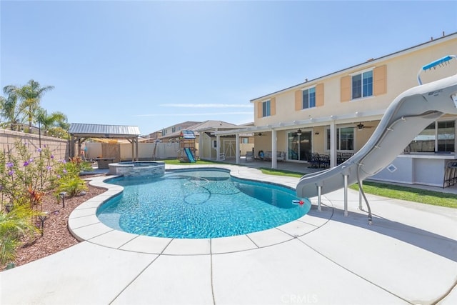 view of pool with a pool with connected hot tub, a water slide, ceiling fan, a fenced backyard, and a patio area