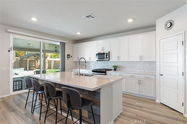 kitchen with visible vents, a sink, tasteful backsplash, appliances with stainless steel finishes, and a breakfast bar area