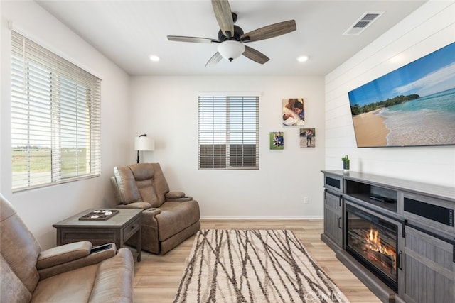 sitting room with visible vents, recessed lighting, light wood-style flooring, a glass covered fireplace, and a ceiling fan