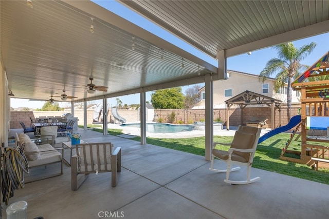 view of patio featuring a ceiling fan, a playground, a fenced backyard, and a fenced in pool