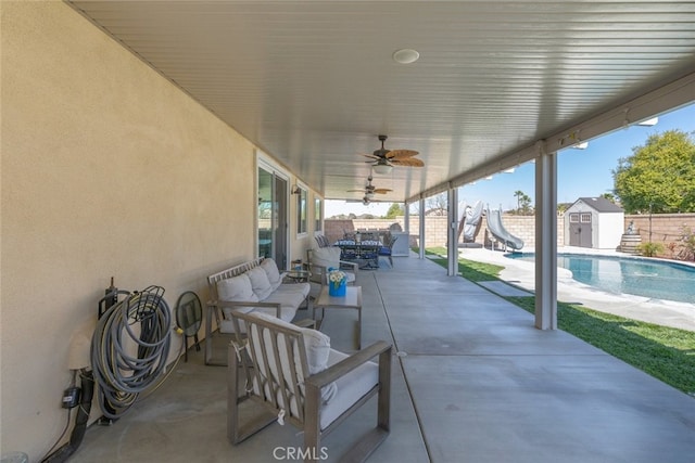 view of patio / terrace featuring a storage unit, an outdoor living space, a fenced backyard, an outdoor structure, and ceiling fan