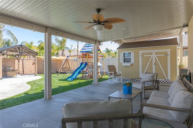 view of patio / terrace with a storage unit, an outdoor living space, a fenced backyard, a playground, and an outdoor structure