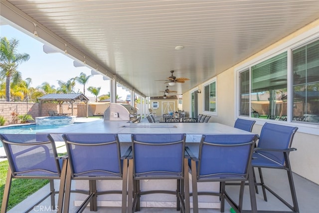 view of patio / terrace featuring outdoor dry bar, a ceiling fan, a pool with connected hot tub, a fenced backyard, and grilling area