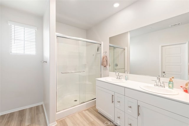 bathroom with a sink, visible vents, wood finished floors, and a shower stall