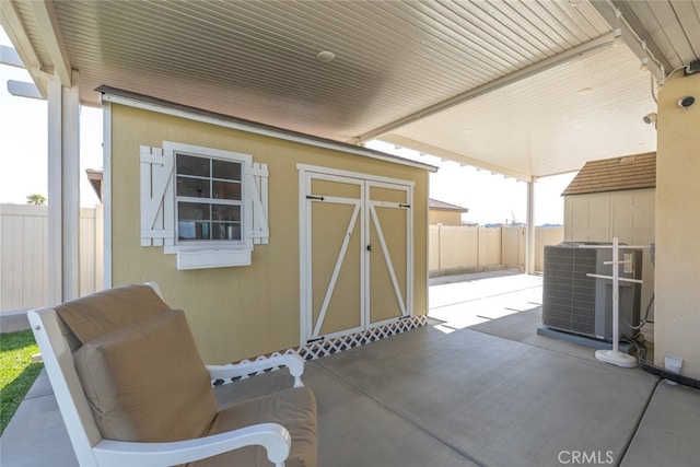 view of patio featuring an outdoor structure, a shed, a fenced backyard, and central AC