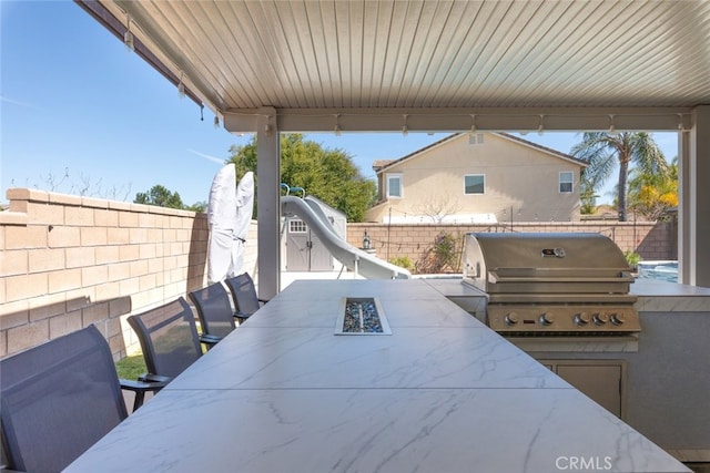 view of patio featuring area for grilling, outdoor dining area, a fenced backyard, and an outdoor kitchen