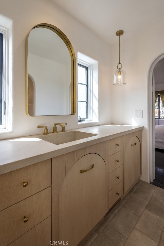 bathroom with connected bathroom, vanity, and stone finish flooring