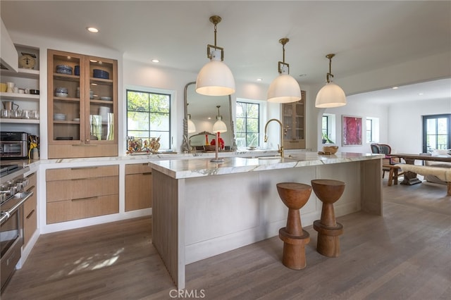 kitchen with modern cabinets, a breakfast bar, dark wood-style floors, recessed lighting, and light stone countertops