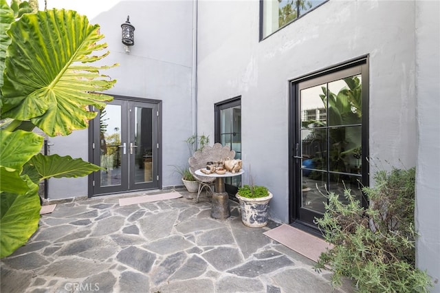 entrance to property featuring a patio area, french doors, and stucco siding