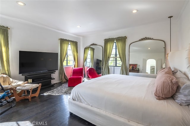 bedroom with arched walkways, recessed lighting, crown molding, and wood finished floors