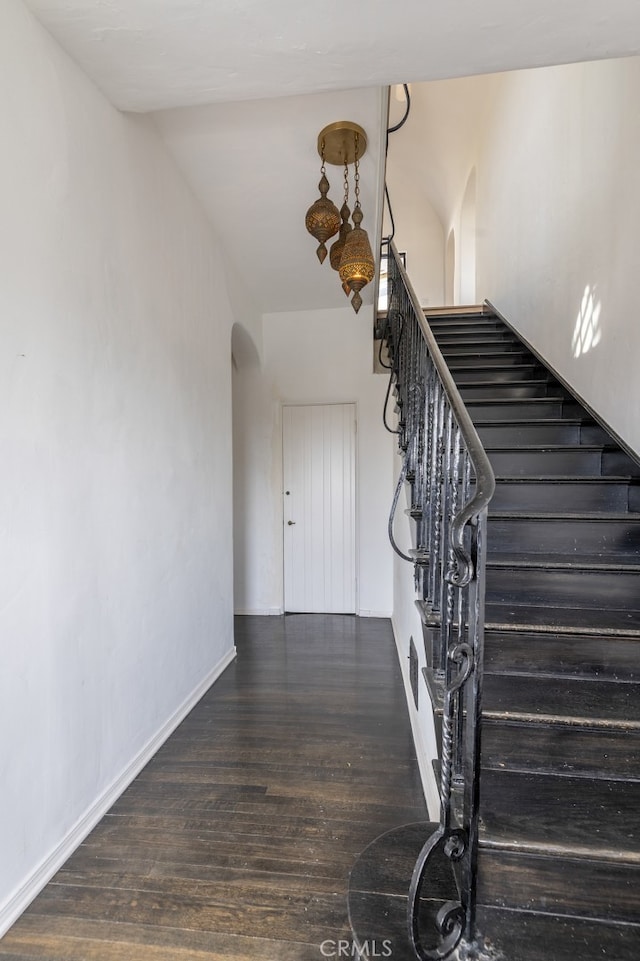 stairway with arched walkways, visible vents, baseboards, and wood finished floors