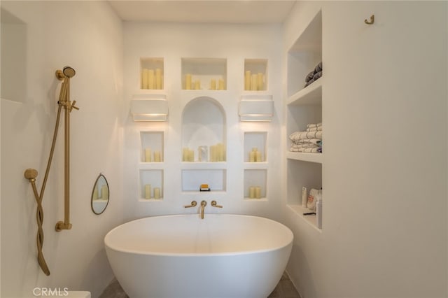 bathroom featuring a freestanding tub and built in shelves