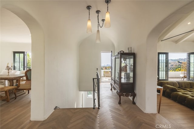 corridor with arched walkways, a high ceiling, and parquet flooring