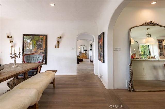 corridor with recessed lighting, visible vents, arched walkways, and wood finished floors