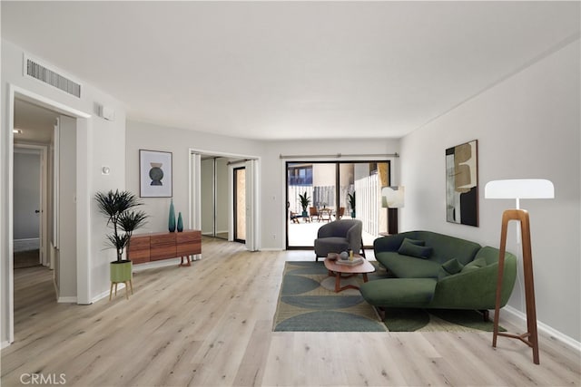 living area featuring light wood-type flooring, visible vents, and baseboards