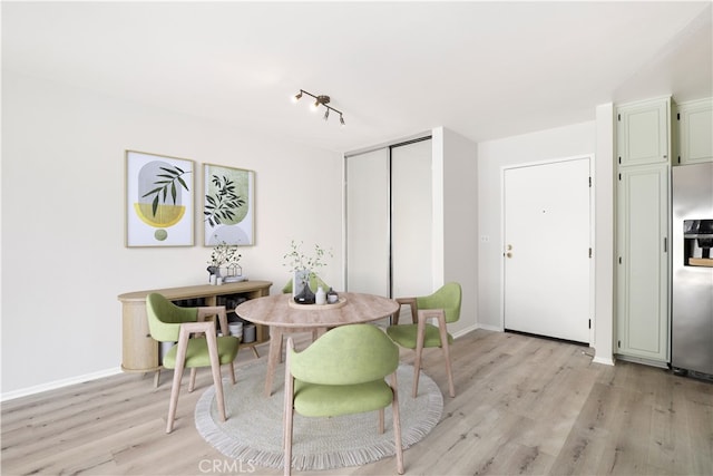 dining space with light wood-type flooring and baseboards