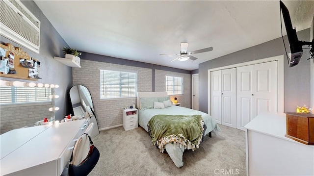 bedroom with a ceiling fan, brick wall, a closet, a wall mounted air conditioner, and light carpet