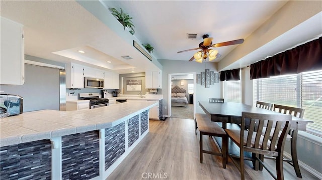 kitchen with visible vents, white cabinets, appliances with stainless steel finishes, a raised ceiling, and light wood-type flooring