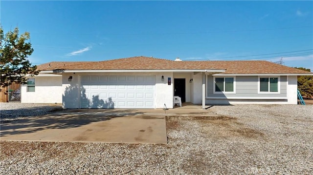 single story home featuring a shingled roof, an attached garage, driveway, and stucco siding