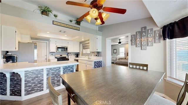 dining area featuring visible vents, ceiling fan, recessed lighting, wood finished floors, and a raised ceiling