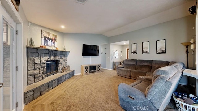 living room featuring visible vents, wood finished floors, a stone fireplace, baseboards, and vaulted ceiling