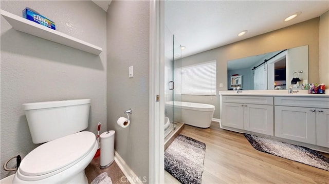 bathroom featuring toilet, a sink, wood finished floors, a shower stall, and double vanity