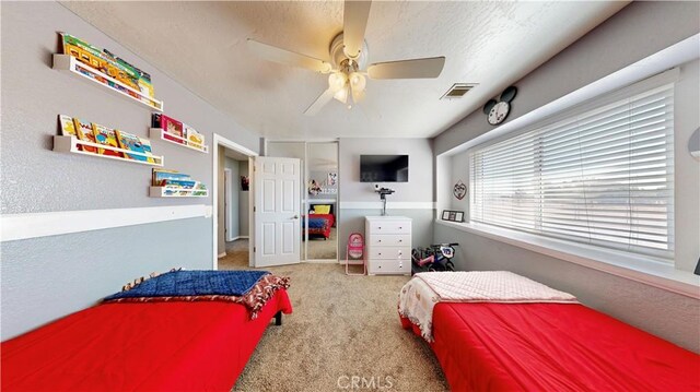 carpeted bedroom featuring a ceiling fan and visible vents