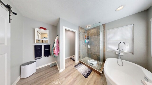 bathroom with baseboards, wood finished floors, a freestanding bath, and a stall shower