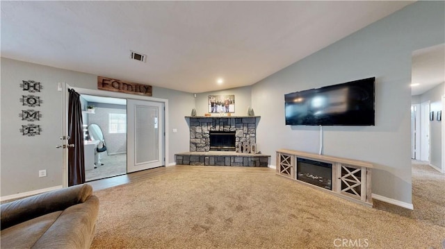 carpeted living area with visible vents, a fireplace, lofted ceiling, and baseboards