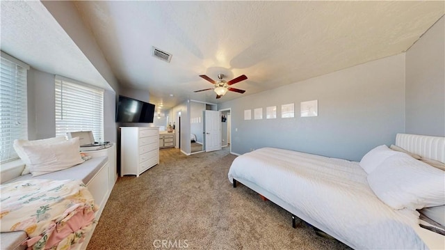 bedroom with a textured ceiling, a ceiling fan, visible vents, and light carpet