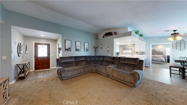 carpeted living room with lofted ceiling, wood finished floors, a ceiling fan, and baseboards