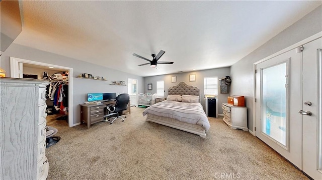 carpeted bedroom featuring a spacious closet, baseboards, a closet, and a ceiling fan