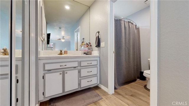 bathroom featuring toilet, vanity, a shower with curtain, and wood finished floors