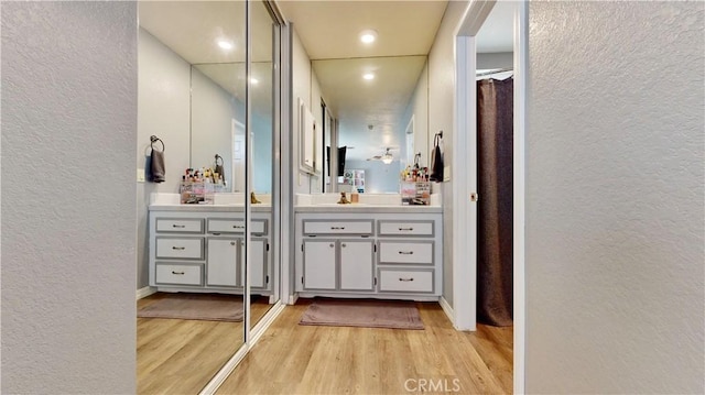 bathroom with vanity, a textured wall, and wood finished floors